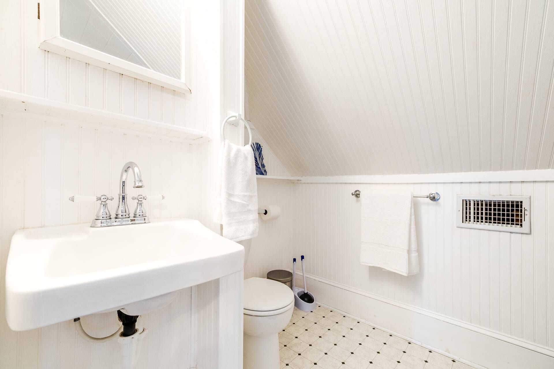 A white bathroom with a sink, toilet, and shower area.