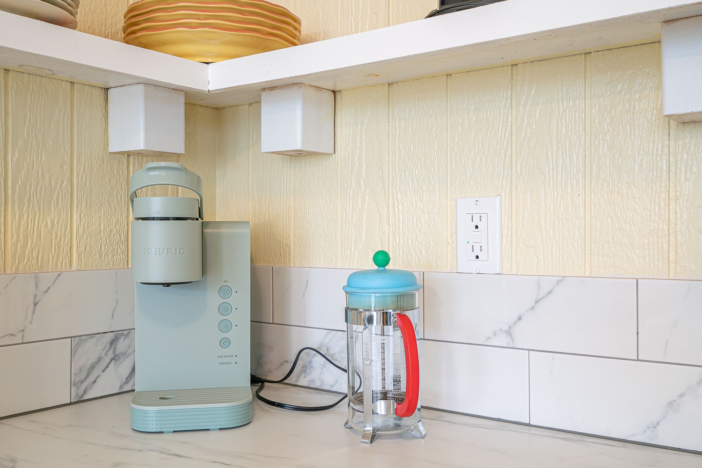 A kitchen with a Keurig coffee maker, a water filtration pitcher, and a white countertop.