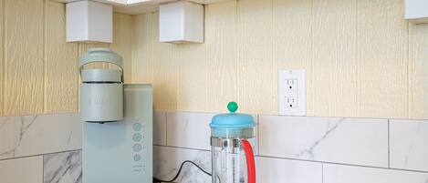 A kitchen with a Keurig coffee maker, a water filtration pitcher, and a white countertop.