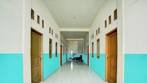 A corridor with doors on both sides, a staircase in the center, and a tiled floor. - OYO Life 93075 Nova Jaya 2 Homestay Syariah (Paciran)