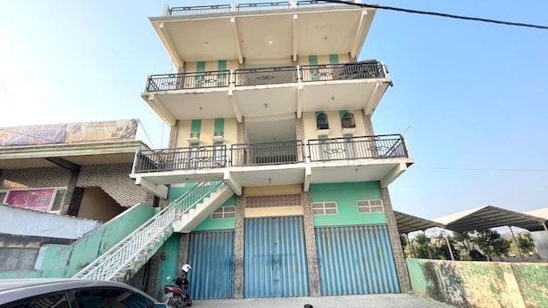 A multi-story building with a balcony on the upper floor, a staircase leading to the entrance, and a car parked in front. - OYO Life 93075 Nova Jaya 2 Homestay Syariah (Paciran)