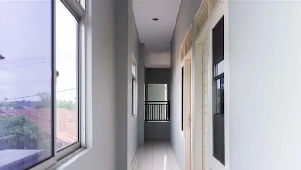 A narrow corridor with a tiled floor, a window on the left, and a door on the right. - Hotel O Home Stay Kembar Syariah (Binjai)