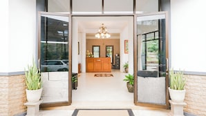 A hotel entrance with a reception desk, potted plants, and a chandelier. - Tripletree Sinergi Hotel Tretes (Prigen)