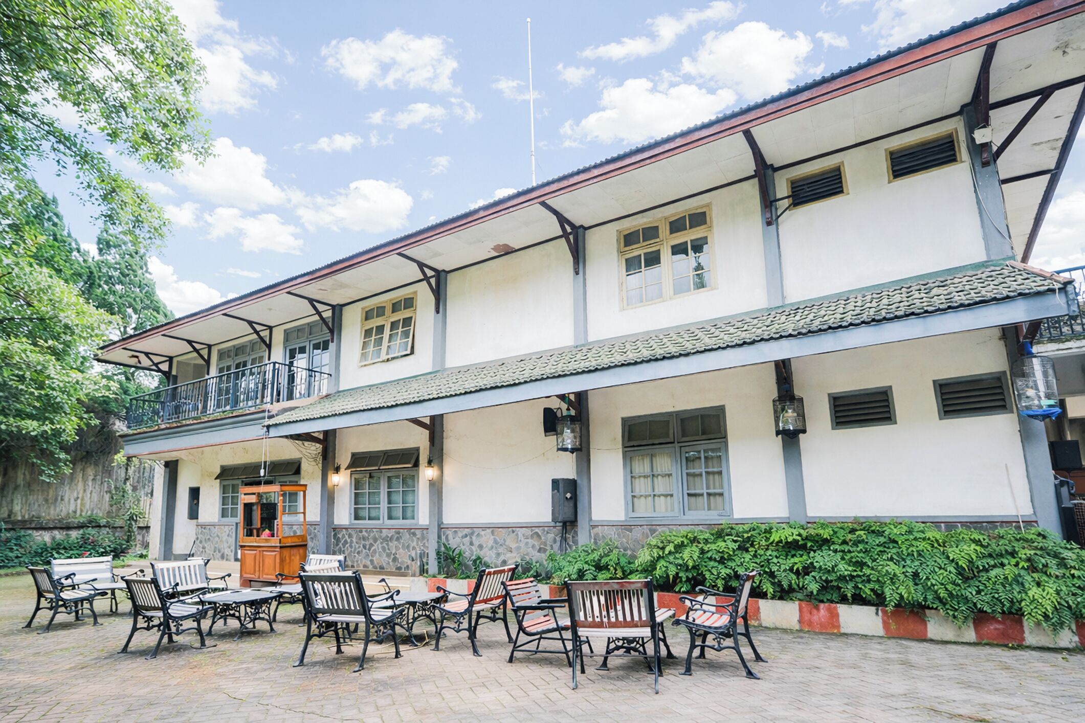 A two-story building with a balcony, outdoor seating area, and a tiled roof.