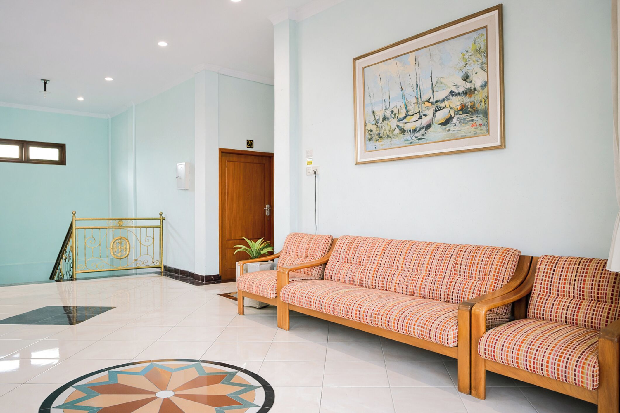 Eine Lobby mit einer Holzdauerbank, einem Gemälde, einer Tür und einer Treppe.