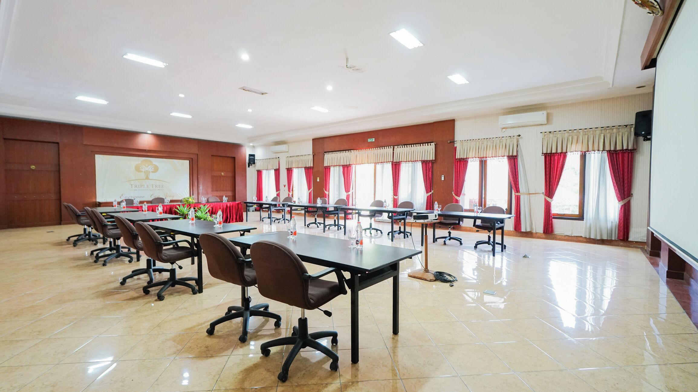 A conference room with multiple tables, chairs, and a projector screen.