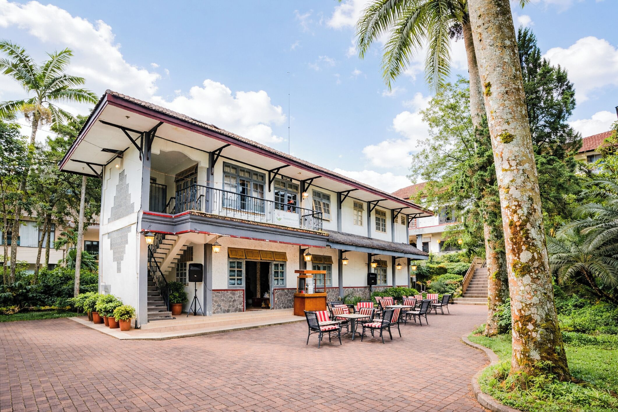 A two-story building with a balcony, outdoor seating area, and a staircase leading to the upper level.