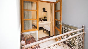 A room with a bed, a bedside table, a mirror, and a window with curtains. - Tripletree Sinergi Hotel Tretes (Prigen)