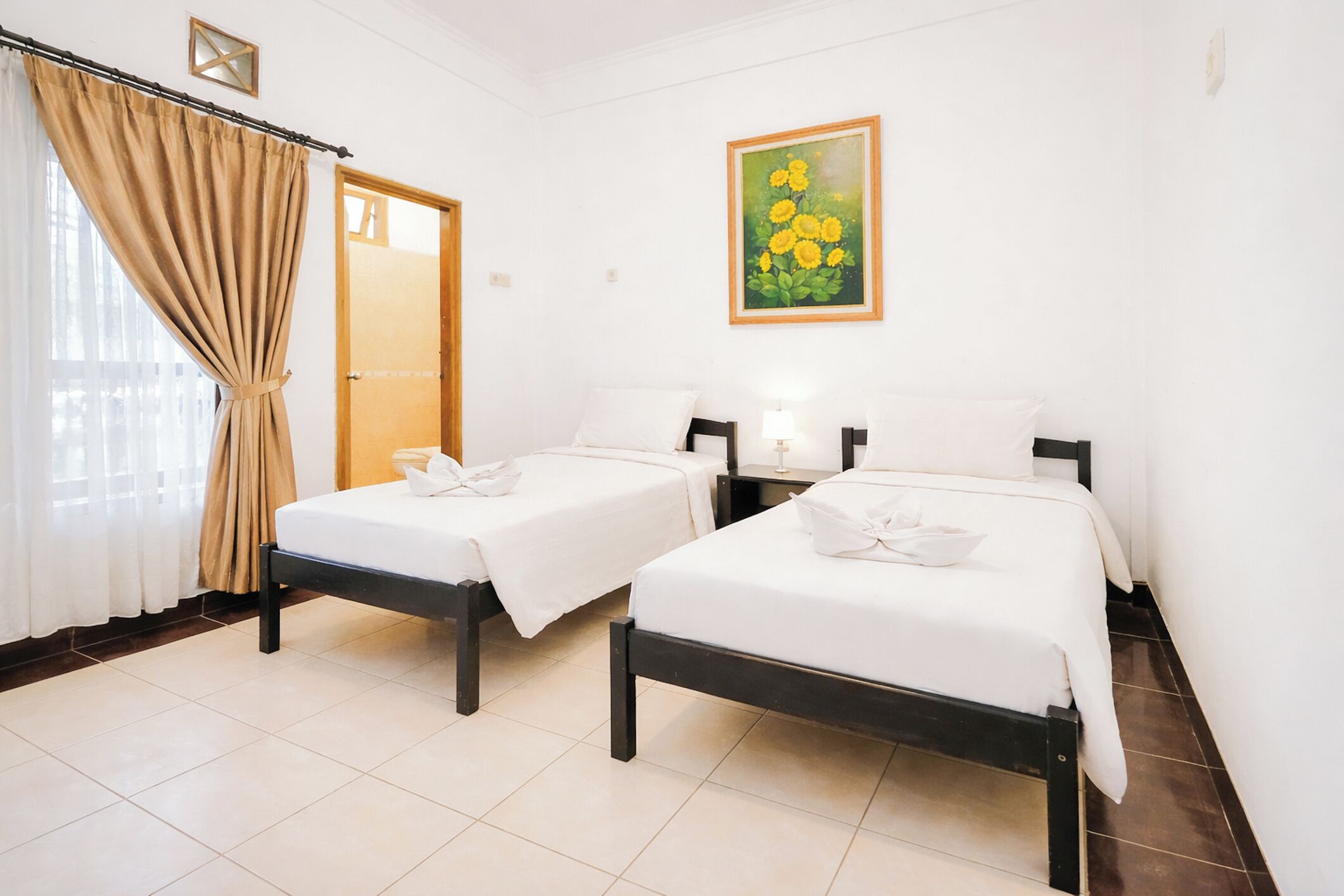 A hotel room with two beds, a painting, a door, and a curtain.