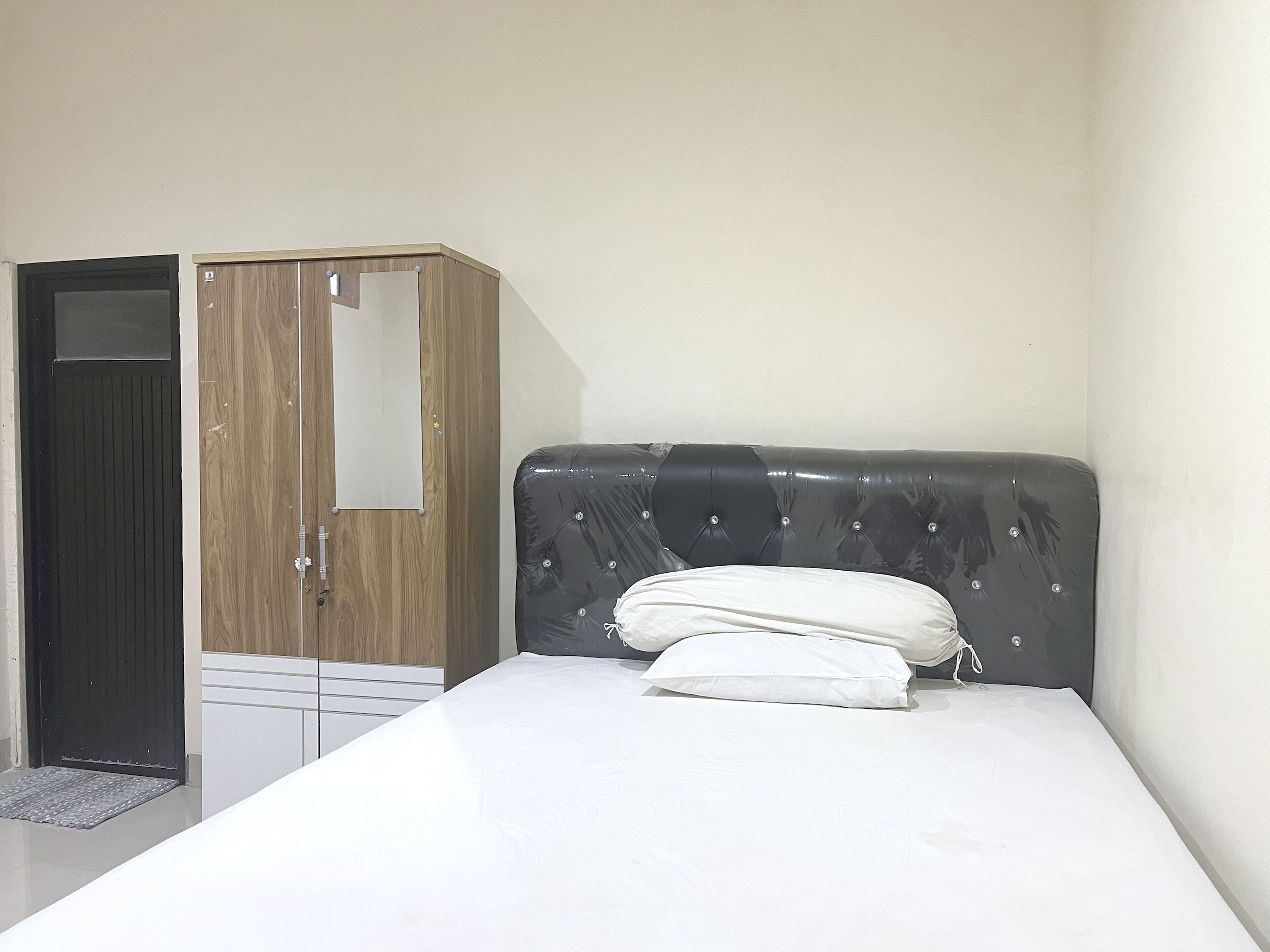 A bedroom with a bed, a wardrobe, and a door.