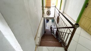 Un escalier avec une rampe en métal, des murs blancs et un sol carrelé.