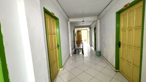 Un couloir avec des portes à cadre vert, des murs blancs et un sol carrelé.