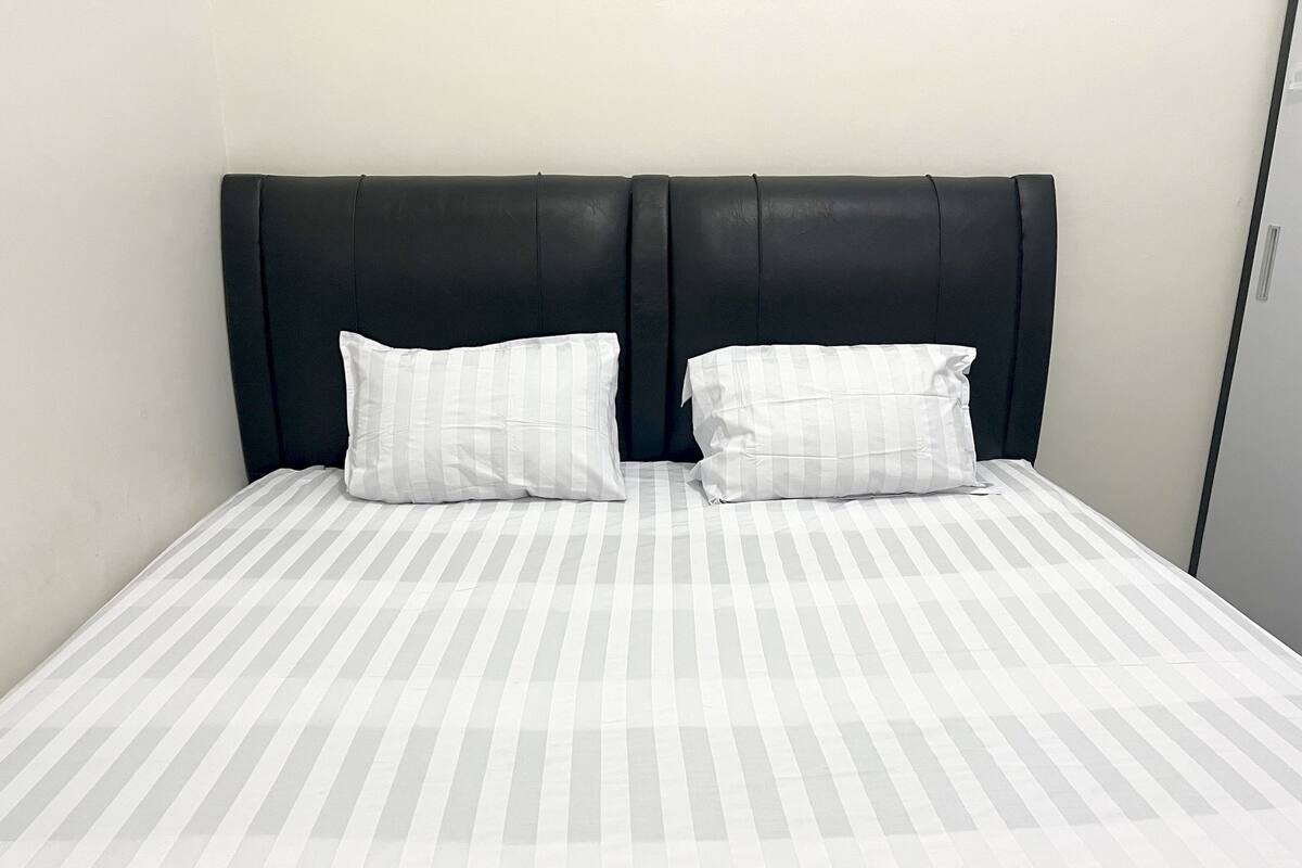 Una cama con colcha a rayas y dos almohadas.