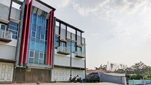 A modern building with large windows, a garage, and a parked motorcycle. - Hotel O Asri Homestay Syariah (Pekanbaru)