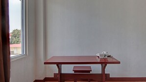 A corner room with a window, a wooden table with a bench, and a white wall. - Hotel O Asri Homestay Syariah (Pekanbaru)