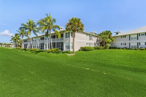 A two-story hotel with a flat roof, large windows, and a well-maintained lawn with palm trees. - Golf course view - Renovated luxury 3bd in Lely, resort pool, tennis, pickleball (Naples)