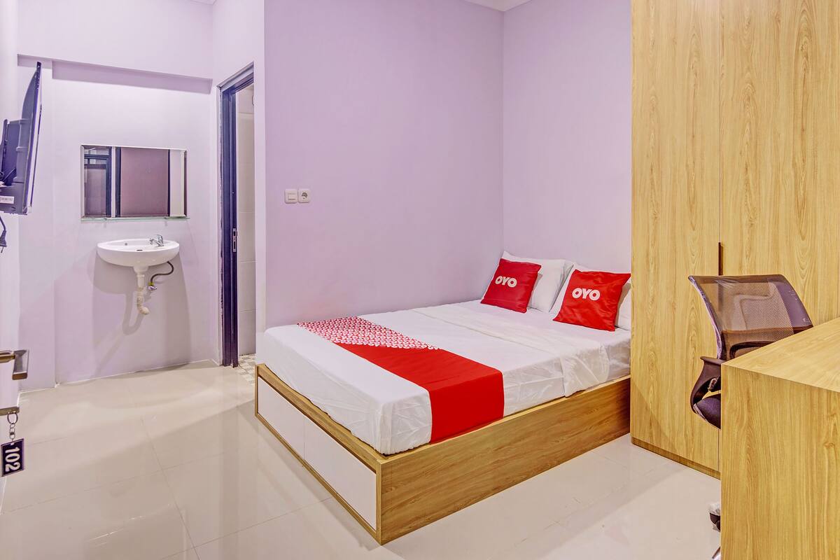 Ein modernes Schlafzimmer mit einem hölzernen Bett, einem weißen Waschbecken und einem Spiegel.