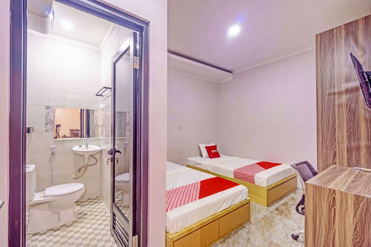 Ein Hotelzimmer mit Bad, zwei Betten, einem Schreibtisch und einem Spiegel.