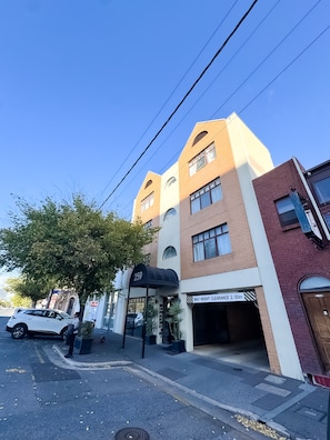 A multi-story building with a black awning, a visible entrance, and a sign indicating a maximum height clearance of 2.00m.