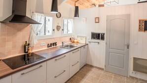 Een moderne keuken met een houten plafond, een ingebouwde magnetron en een zwarte afzuigkap.