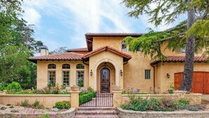 Una casa de estilo mediterráneo con fachada de estuco, techo de tejas y una entrada central con un pequeño porche.