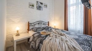A neatly made bed with a patterned bedspread, two bedside lamps, and a small table with a cup and saucer. - Park Ribnjak Apartment (Zagreb)