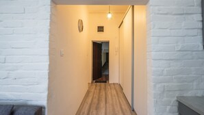 A narrow hallway with wooden flooring and white brick walls. - Park Ribnjak Apartment (Zagreb)