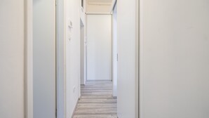 A narrow, light-colored hallway with white walls and a wooden floor. - Park Ribnjak Apartment (Zagreb)