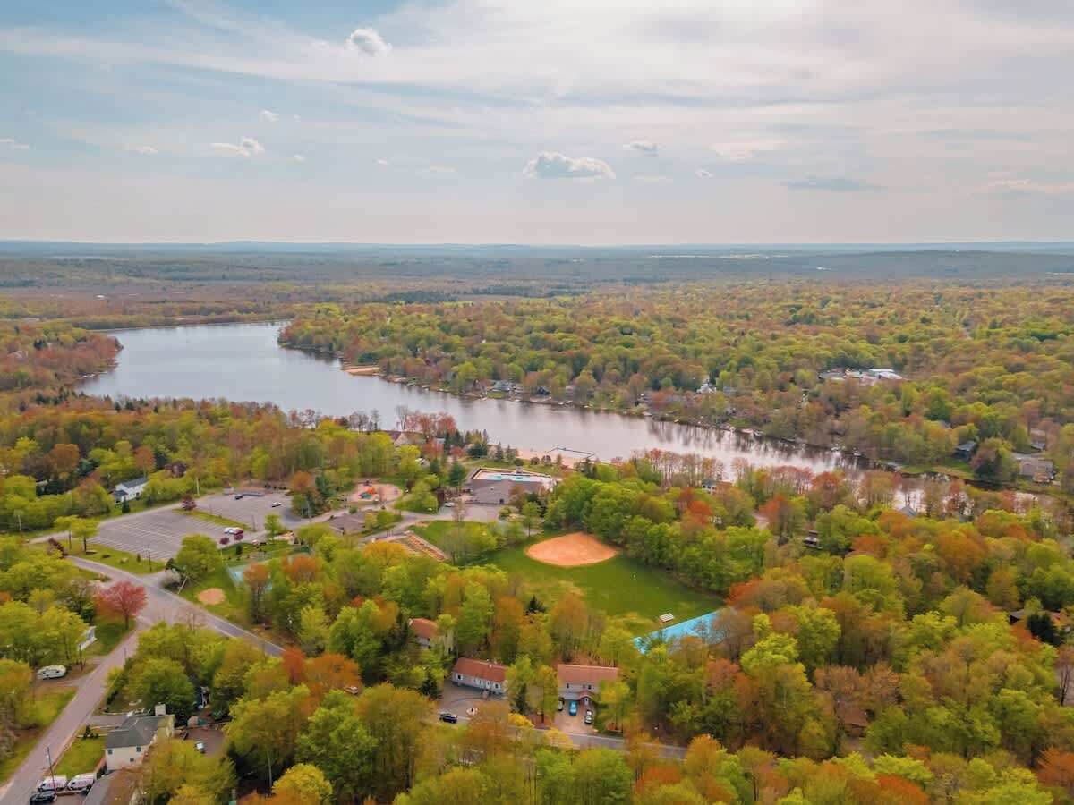 A residential area with houses, a baseball field, and a lake.