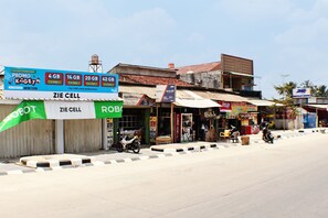 Straßenansicht mit verschiedenen Geschäften, darunter ein Mobilfunkladen und eine Apotheke.