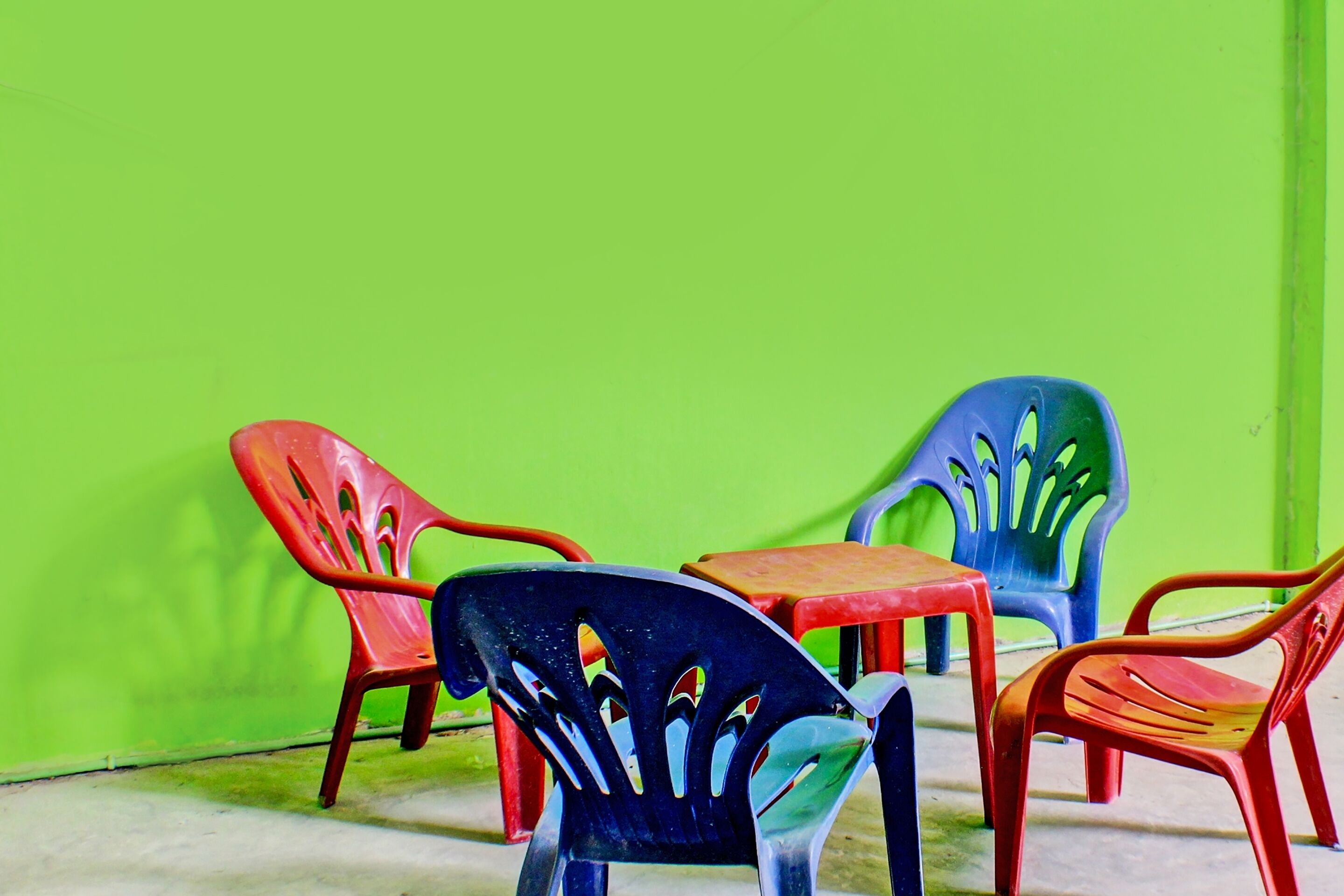 A row of plastic chairs against a green wall.