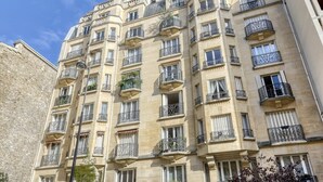 Um edifício de vários andares com varandas, janelas amplas e fachada de pedra.