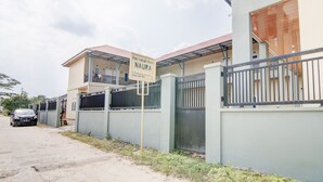 A residential building with a gated entrance, a signboard, and a parked car. - OYO 93087 Wisma Apel Syariah (Pekanbaru)