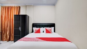 A neatly arranged hotel room with a bed, a wardrobe, and a curtain. - OYO 93087 Wisma Apel Syariah (Pekanbaru)
