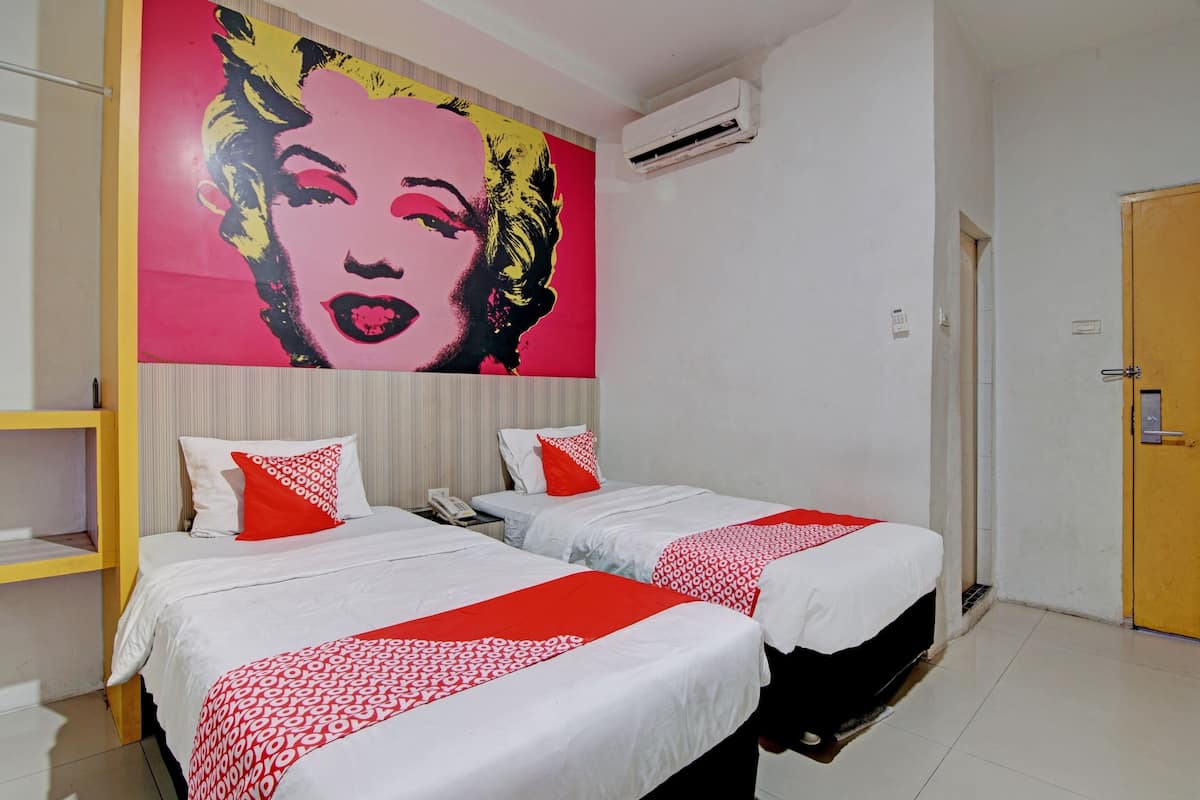 A hotel room with two beds, a large pop art mural on the wall, and a wooden door.
