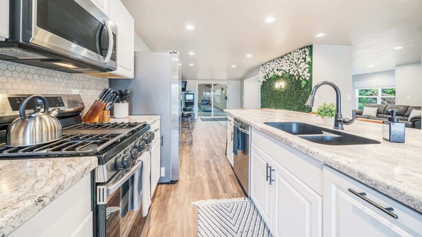 A modern kitchen with stainless steel appliances, a large island with a sink, and a decorative wall with greenery. - Sleeps 20 * 4,400 Sq Ft * Indoor Heated Pool (Brillion)