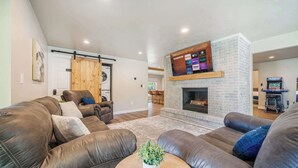 A modern living room with a fireplace, leather sofas, a mounted TV, and a wooden sliding door. - Sleeps 20 * 4,400 Sq Ft * Indoor Heated Pool (Brillion)