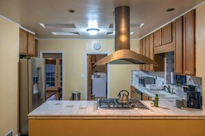 A kitchen with a central island, stainless steel appliances, and wooden cabinets. - Sam Hughes Retreat by Velo (Tucson)