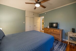 A bedroom with a bed, a dresser, a television, and a ceiling fan. - Sam Hughes Retreat by Velo (Tucson)
