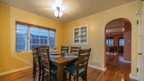 A dining area with a wooden table and chairs, a window with blinds, and a cabinet with glass doors.