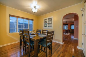 A dining area with a wooden table and chairs, a window with blinds, and a cabinet with glass doors.