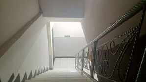 A staircase with a metal railing, white walls, and a ceiling light. - OYO 93090 Multi Plus Inn (Jayapura)