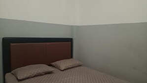 A small, single-bed room with a wooden headboard and two pillows. - OYO 93090 Multi Plus Inn (Jayapura)
