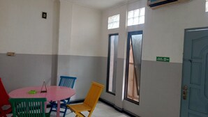 A room with a round table, colorful chairs, a blue door, and windows with curtains. - OYO 93090 Multi Plus Inn (Jayapura)