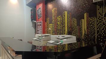 Un área de cocina moderna con un mural de la ciudad en la pared, una cafetera e impresora sobre la encimera.