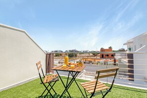 Enjoy the view from this balcony with a table and two chairs.