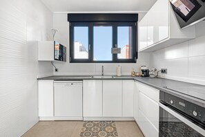 Enjoy a city view from the kitchen window, featuring a dishwasher and sleek cabinetry.