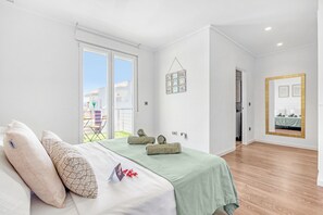Relax in a serene bedroom with a large bed, framed picture, and sliding glass door leading to an outdoor area.