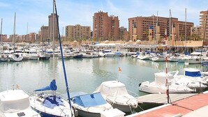 A marina with numerous boats docked, surrounded by high-rise buildings. - Ideal apartment for golf lovers or families, with communal pool in Mijas Golf! (Mijas costa)