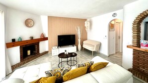 A living room with a white sofa, a television, a fireplace, and a decorative mirror. - Ideal apartment for golf lovers or families, with communal pool in Mijas Golf! (Mijas costa)